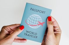 two hands holding up a passport with the word world traveler written in red on it