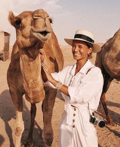 a woman is petting a camel in the desert