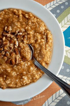 a bowl of oatmeal with pecans on top and spoon in it