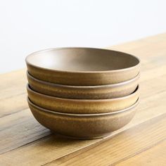 three brown bowls sitting on top of a wooden table