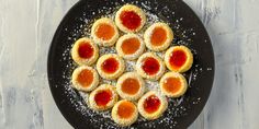 a black plate topped with small pastries covered in jelly