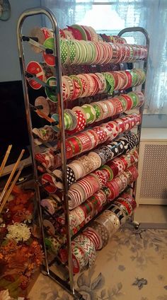 a metal rack filled with lots of different types of wrapping paper next to a window