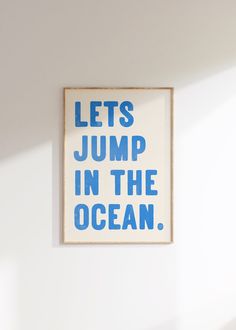 a blue and white poster with the words lets jump in the ocean on it's wall