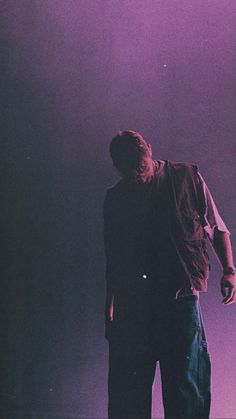 a man standing in front of a purple light with his back turned to the camera