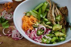 a white bowl filled with meat and veggies on top of a wooden table