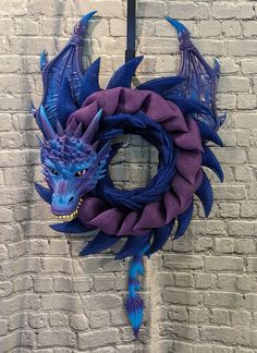 a purple and blue dragon wreath hanging on a brick wall