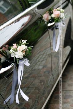 two flowers are tied to the side of a car with white ribbon and ribbons on it