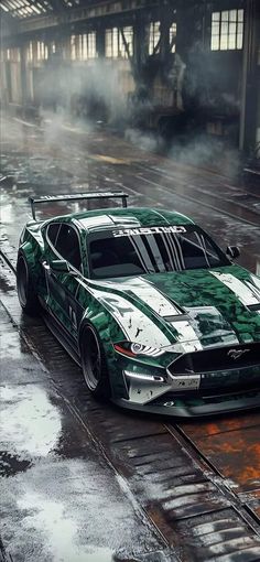 a green sports car with white stripes driving down a wet track in the rain,