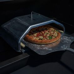 a pizza sitting on top of a metal tray in an oven with it's door open