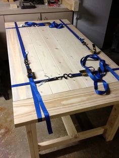 a table that has been made with wood and blue ribbon tied around the edge to it