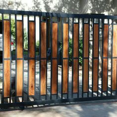 an iron gate with wooden panels on the sides and side walk in front of it