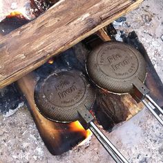 two frying pans sitting on top of a fire