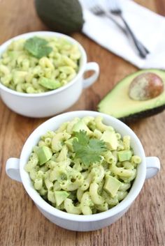 two bowls filled with macaroni salad next to an avocado