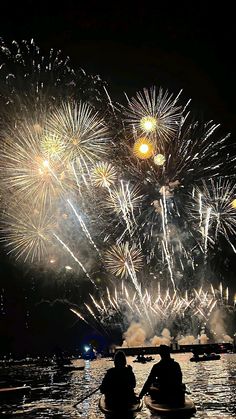 two people in a row boat watching fireworks