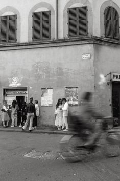 black and white photograph of people standing in front of a building