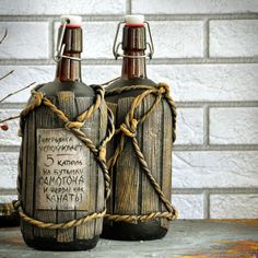 two bottles with writing on them sitting next to each other in front of a brick wall