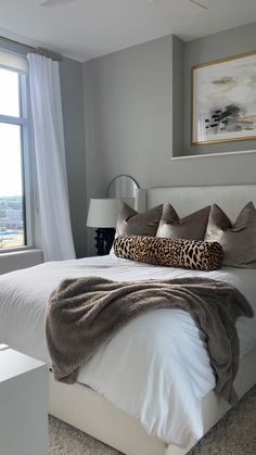 a bedroom with a large bed and a window overlooking the cityscape is pictured in this image