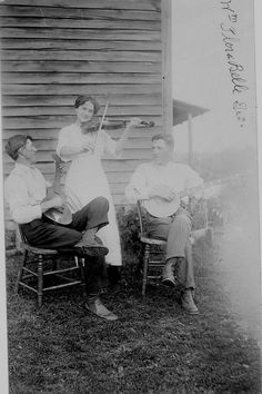 an old black and white photo of three people sitting on lawn chairs, one holding a violin