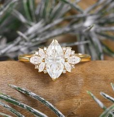 an engagement ring with a pear shaped diamond surrounded by smaller pears on top of a piece of wood