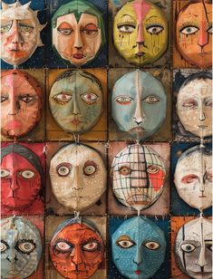 many different faces are hanging from strings on the wall, and one is painted with multiple colors