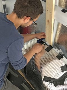 a man is working on the side of a metal sheet with a pair of pliers