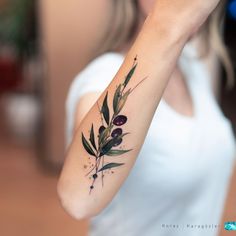 a woman's arm with an olive branch tattoo on it