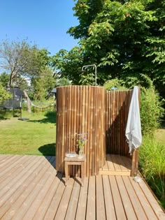 an outdoor shower in the middle of a wooden deck with a chair and table next to it