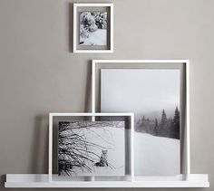 three white frames on a shelf with pictures