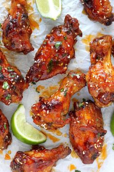 chicken wings with lime wedges and sesame seeds on parchment paper, ready to be eaten