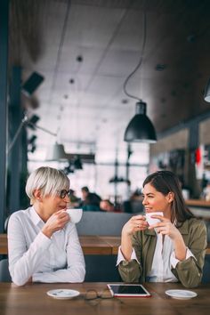 two women sitting at a table drinking coffee