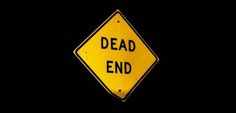 a yellow dead end sign in the dark