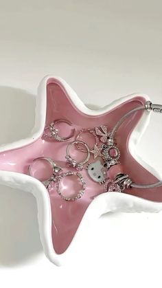 a pink and white star shaped tray with lots of jewelry on it's sides