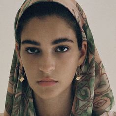 a young woman wearing a headscarf and looking at the camera with an intense look on her face