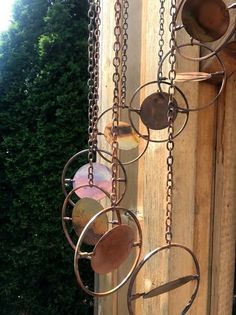 an outdoor wind chime hanging from a wooden post with chains and discs attached to it