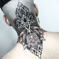 the back of a man's head with an intricate tattoo design on his neck