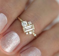 a woman's hand holding a ring with diamonds on it and a diamond in the middle