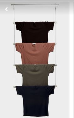 four t - shirts hanging on a clothes rack with three different colors and sizes in them