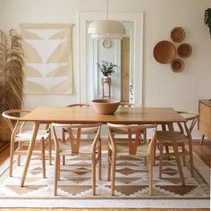 a dining room table and chairs in front of a mirror with plants on the wall