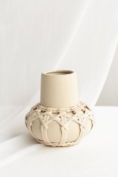 a white vase sitting on top of a table next to a white wall and floor