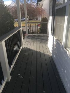 an empty porch with white walls and black railing