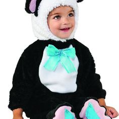 a baby dressed in a black and white cat costume sitting on the floor with her feet up