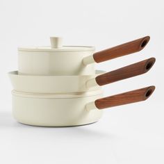 three white pots with wooden spoons in them