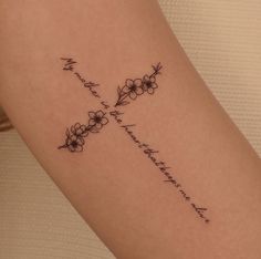 a woman's arm with a cross and flowers tattoo on the back of it