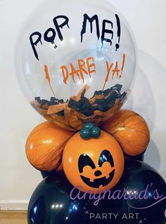 an orange and black balloon sitting on top of a blue ball with the words pop me i dare ya