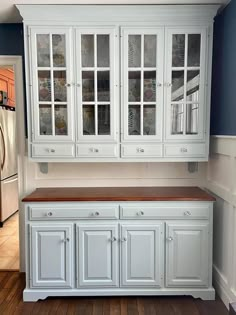 an empty kitchen with white cabinets and wood flooring in the middle of the room