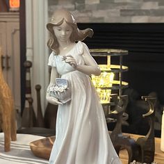 a figurine of a woman holding a basket in front of a fire place