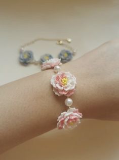 a woman's arm with flowers and pearls attached to the bracelets on it