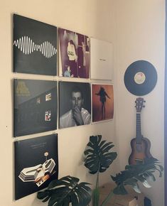 there are many pictures hanging on the wall next to a plant and record player in this room