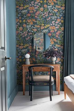 a bedroom with blue walls and floral wallpaper on the walls, along with a chair