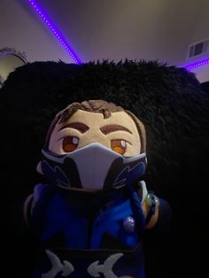 a stuffed animal wearing a face mask and jacket in a room with purple lights on the ceiling